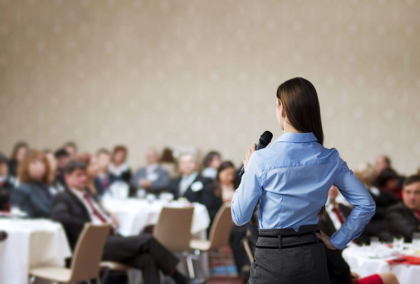 A woman speaking to an audience in a conference room.