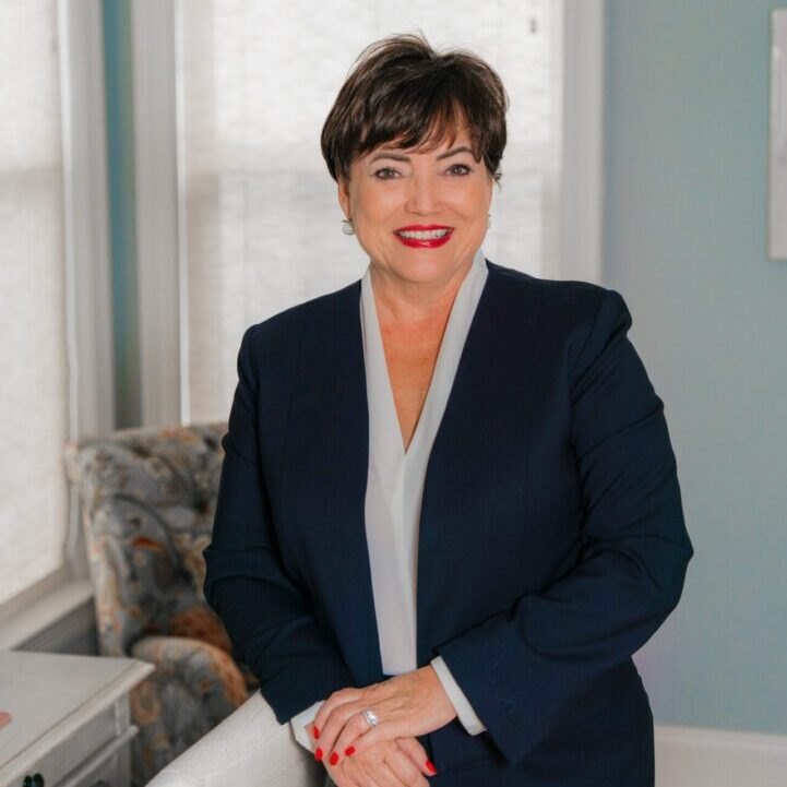 Professional woman in a navy suit poses confidently indoors.